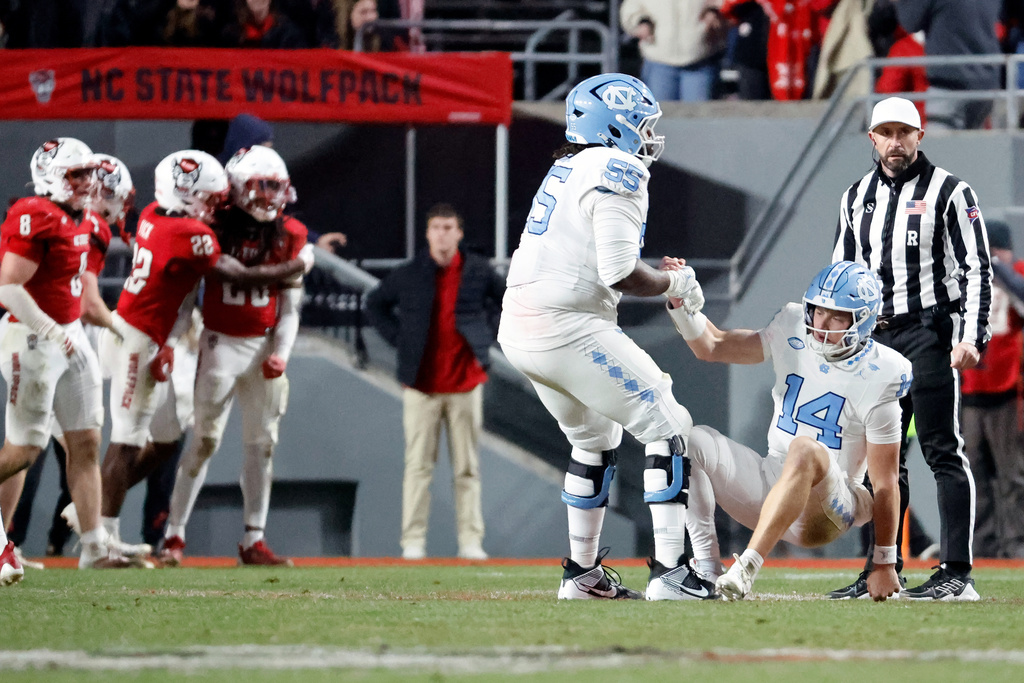 North Carolina offensive lineman Jakai Moore (55) helps quarterback Max Johnson (14) during the second half of an NCAA college football game against North Carolina State in Raleigh, N.C., Saturday, Nov. 29, 2025. (AP Photo/Karl DeBlaker)