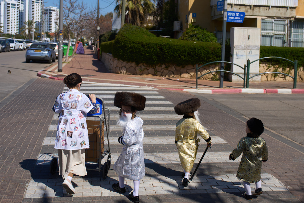Ultra-Orthodox children wearing costumes during the purim festival cross a street in Netanya, Israel, Tuesday, March 3, 2026. (AP Photo/Ariel Schalit)