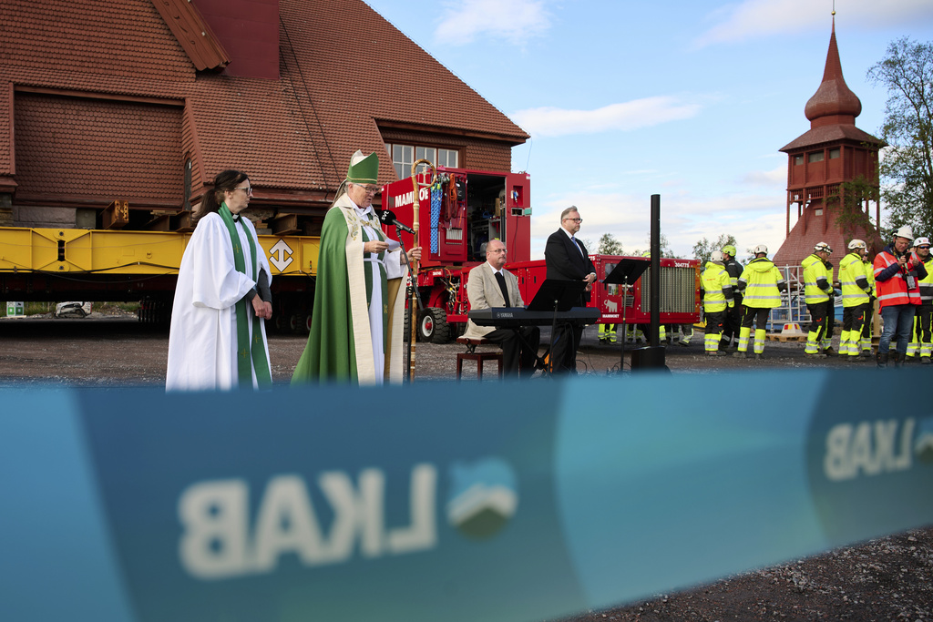Vicar Lena Tjarnberg, left, and Bishop Asa Nystrom bless the Kiruna Church, a Sami style wooden Swedish Lutheran church, called Kiruna Kyrka in Swedish, in Kiruna, Sweden, Tuesday, Aug. 19, 2025, shortly before being moved along a 5-kilometer (3-mile) route east to a new city center as part of the town's relocation. (AP Photo/Malin Haarala)