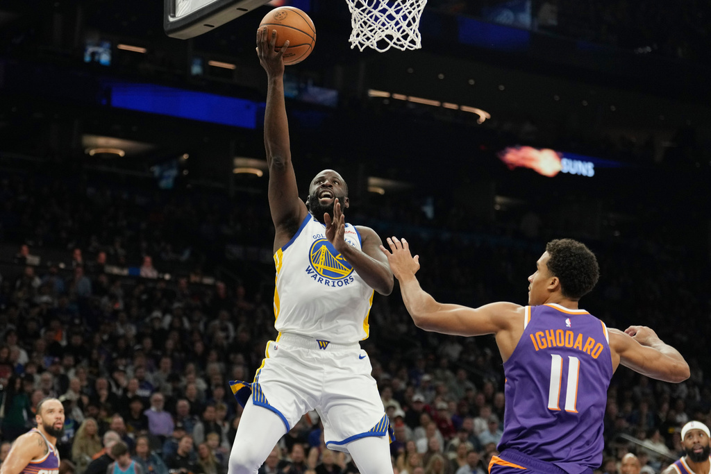 Golden State Warriors forward Draymond Green, left, drives past Phoenix Suns forward Oso Ighodaro (11) to score during the first half of an NBA basketball game Thursday, Dec. 18, 2025, in Phoenix. (AP Photo/Ross D. Franklin)