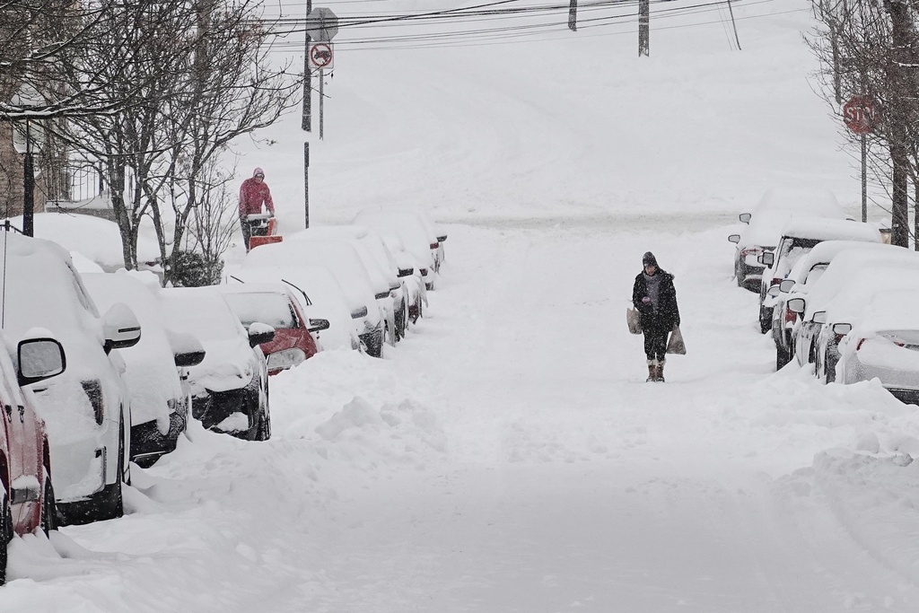 A person carries grocery bags up a residential street during a winter storm Sunday, Jan. 25, 2026, in Cincinnati. (AP Photo/Joshua A. Bickel)