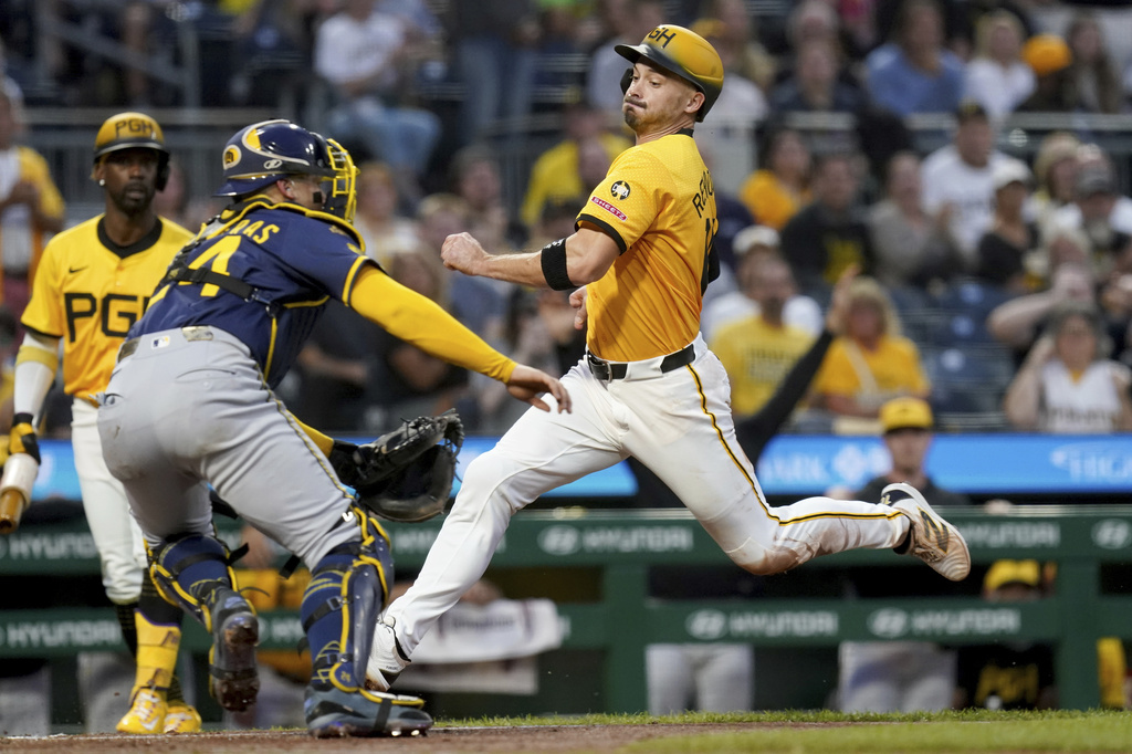 Pittsburgh Pirates' Bryan Reynolds, right, scores as Milwaukee Brewers catcher William Contreras, front left, waits for a late throw during the third inning of a baseball game Friday, Sept. 5, 2025, in Pittsburgh. (AP Photo/Matt Freed)