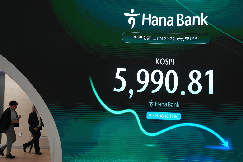 Dealers walk past the screen showing the Korea Composite Stock Price Index (KOSPI) at a dealing room of Hana Bank in Seoul, South Korea, Tuesday, Oct. 13, 2026. (AP Photo/Lee Jin-man)