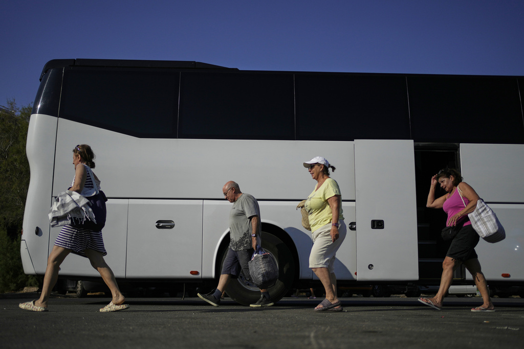 People arrive by bus at Avlaki beach about 42 kilometers (26 miles) east of Athens, Greece, Wednesday, Aug. 19, 2025. (AP Photo/Thanassis Stavrakis)