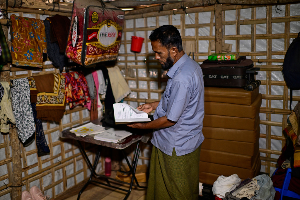 Mohib Ullah, father of 13-year-old Mohammed, shows his son's school books inside their shelter in the Rohingya refugee camp in Cox's Bazar, Bangladesh, Saturday, Nov. 22, 2025. (AP Photo/Mahmud Hossain Opu)