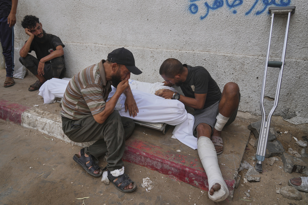 Abdul Basit Abu Khater, 30, right, mourns over the bodies of his nephews who were killed in an Israeli military strike on a school used as a shelter, outside Al-Shifa Hospital, in Gaza City, Friday, Aug. 22, 2025. (AP Photo/Abdel Kareem Hana)