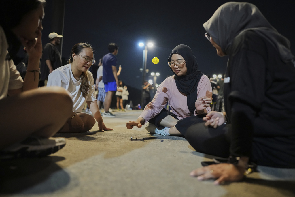 People play knucklebones ball during a community playing gathering in Jakarta, Indonesia, Friday, July 11, 2025. (AP Photo/Dita Alangkara)