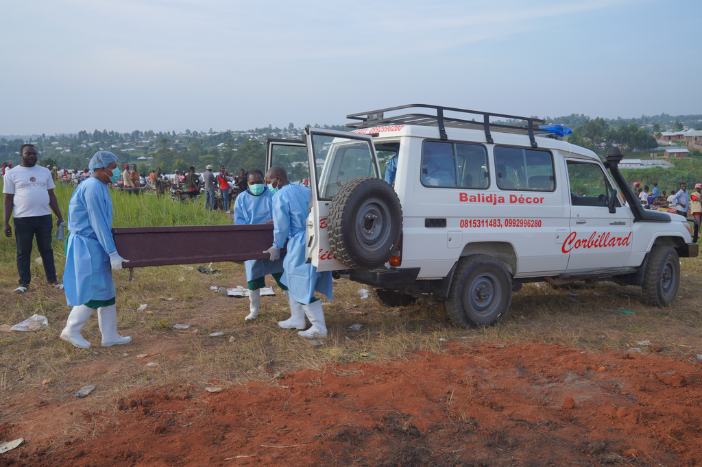 People dressed in protective gear unload a coffin containing the remains of six-year-old Baudjo Baraka Jules, who died of Ebola, for a burial service in Bunia, Ituri province, eastern Congo, Tuesday, Aug. 18, 2026. (AP Photo/Dieudonne Dirole)