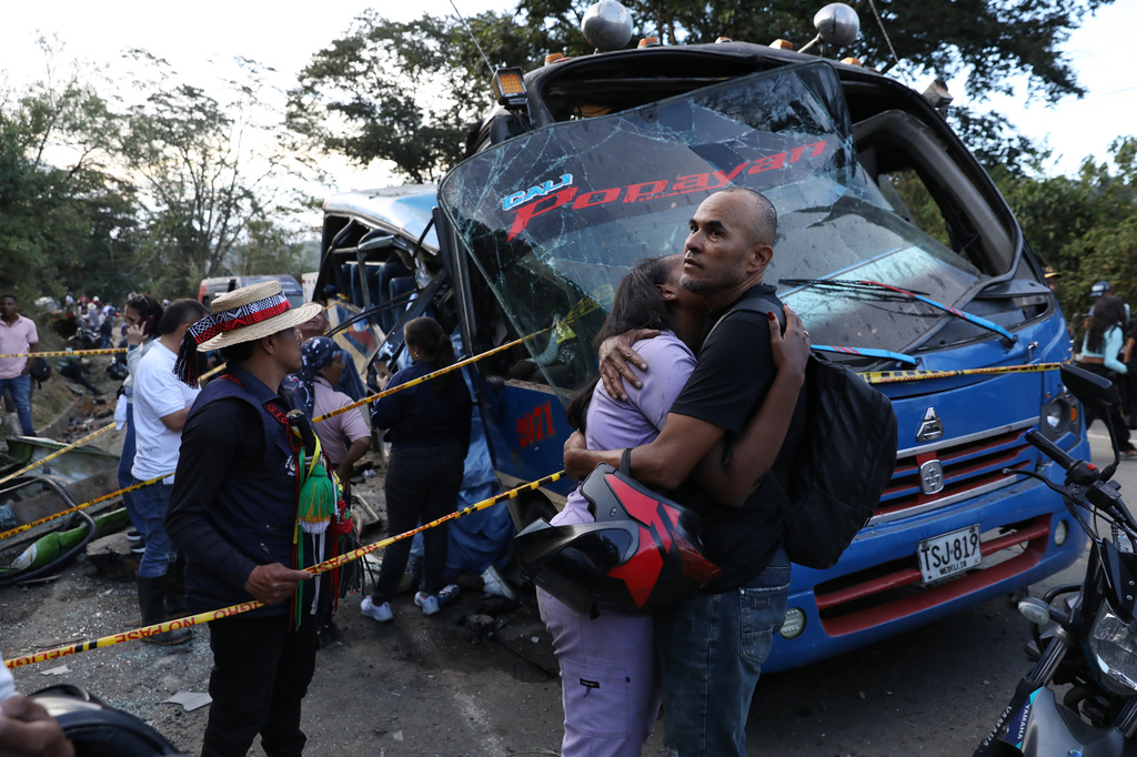 Relatives of victims embrace in front of a bus hit by an explosive device on the Pan-American Highway in Cajibio, Colombia, Saturday, April 25, 2026, after an attack blamed by authorities on dissident groups of the former FARC rebels killed at least a dozen people. (AP Photo/Santiago Saldarriaga)