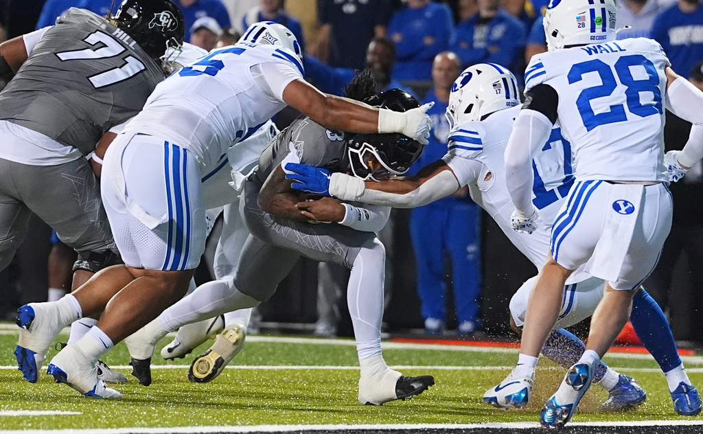 Colorado quarterback Kaidon Salter, center, runs for a touchdown as Brigham Young defensive tackle John Taumoepeau, left, and linebacker Jack Kelly defend in the first half of an NCAA college football game Saturday, Sept. 27, 2025, in Boulder, Colo. (AP Photo/David Zalubowski)
