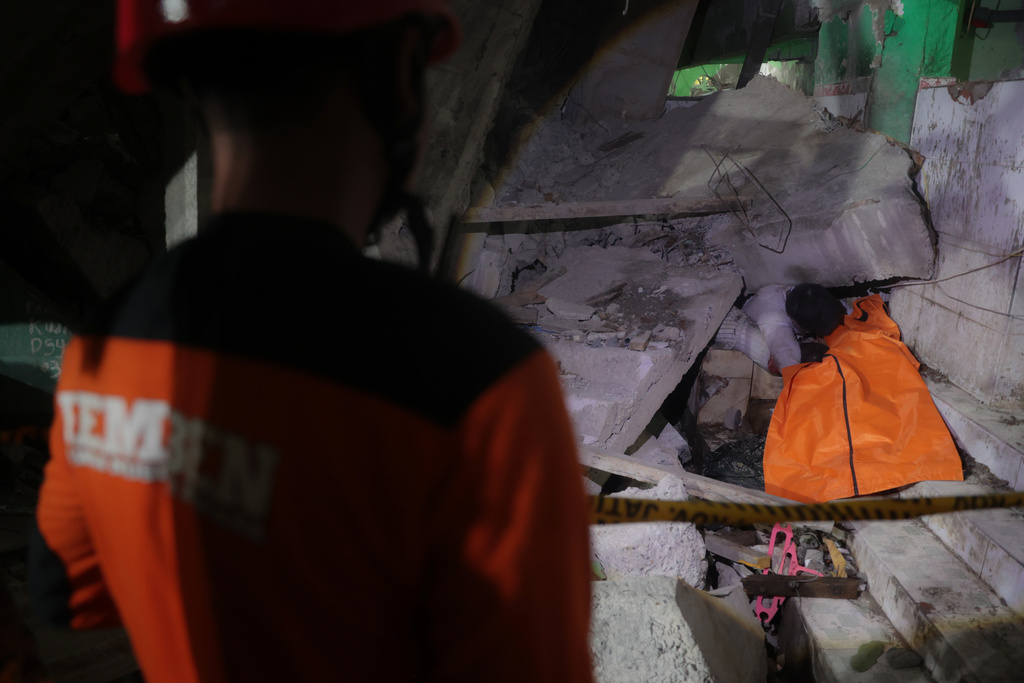 EDS NOTE: GRAPHIC CONTENT - A rescuer attempts to remove the trapped body of a victim after a building collapsed at an Islamic boarding school in Sidoarjo, East Java, Indonesia, Monday, Sept. 29, 2025. (AP Photo/Trisnadi)