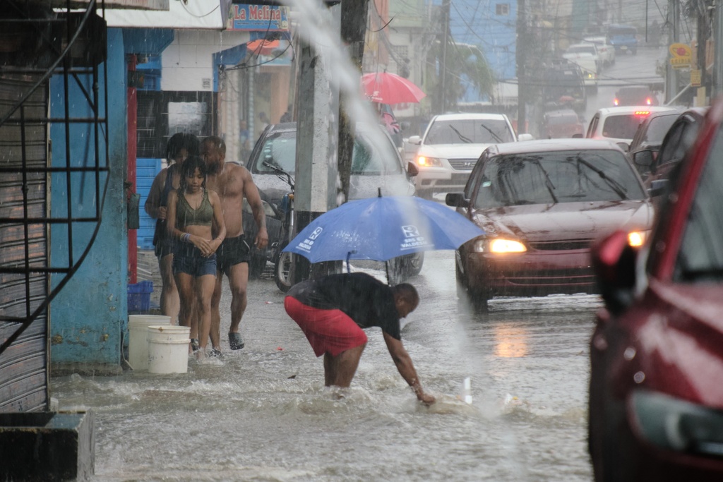 People walk in a street flooded by rains caused by Tropical Storm Melissa in Santo Domingo, Dominican Republic, Friday, Oct. 24, 2025. (AP Photo/Ricardo Hernandez)