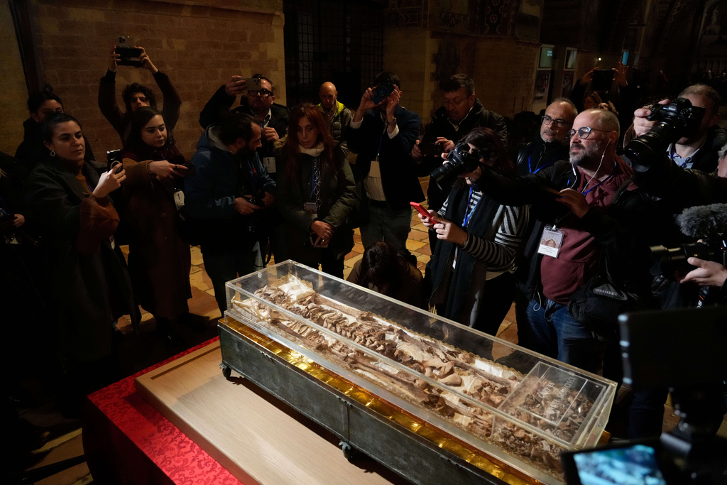 Journalists record the remains of Francis of Assisi inside the Basilica of St. Francis of Assisi in Assisi, Italy, Saturday, Feb. 21, 2026, on the eve of a public exposition beginning Feb. 22 to mark the 800th anniversary of his death in 1226. (AP Photo/Gregorio Borgia)