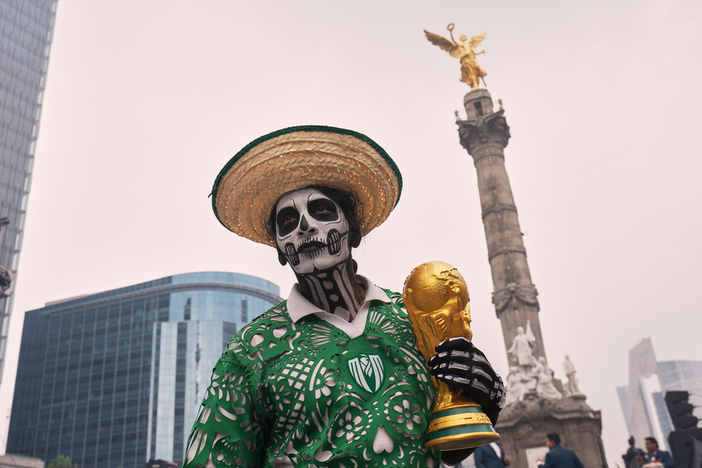 A dancer holds a replica of the World Cup trophy as soccer fans stand along Reforma Avenue in Mexico City, Saturday, June 6, 2026 ahead of the FIFA World Cup. (AP Photo/Moises Castillo)