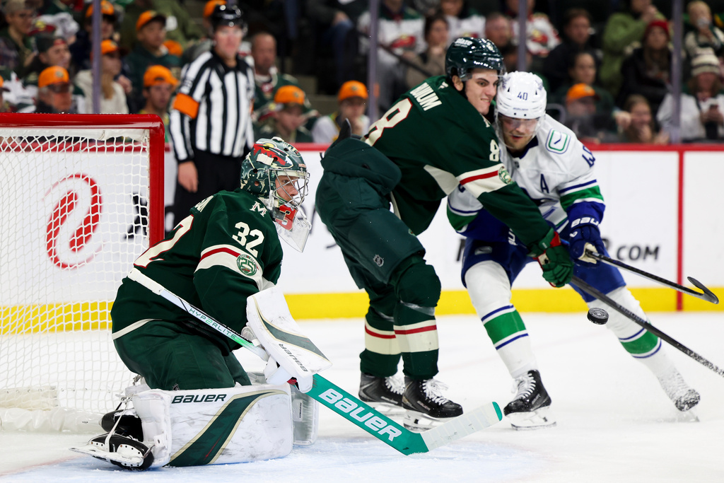 Minnesota Wild goaltender Filip Gustavsson (32) prepares to save the puck while Wild defenseman Zeev Buium (8) works Vancouver Canucks center Elias Pettersson (40) away from the net during the second period of an NHL hockey game, Saturday, Nov. 1, 2025, in St. Paul, Minn. (AP Photo/Ellen Schmidt)