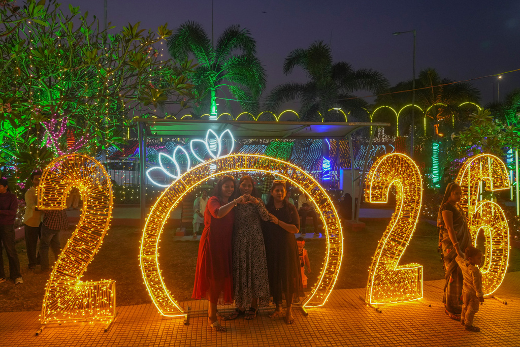 People pose for pictures near illuminated decorations on New Year's Eve in Mumbai, India, Wednesday, Dec. 31, 2025. (AP Photo/Rafiq Maqbool)