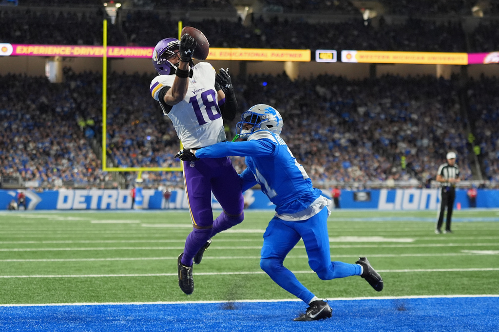 FILE - Minnesota Vikings wide receiver Justin Jefferson (18) catches a touchdown pass ahead of Detroit Lions cornerback Amik Robertson (21) during the first half of an NFL football game Nov. 2, 2025, in Detroit. (AP Photo/Ryan Sun, File)