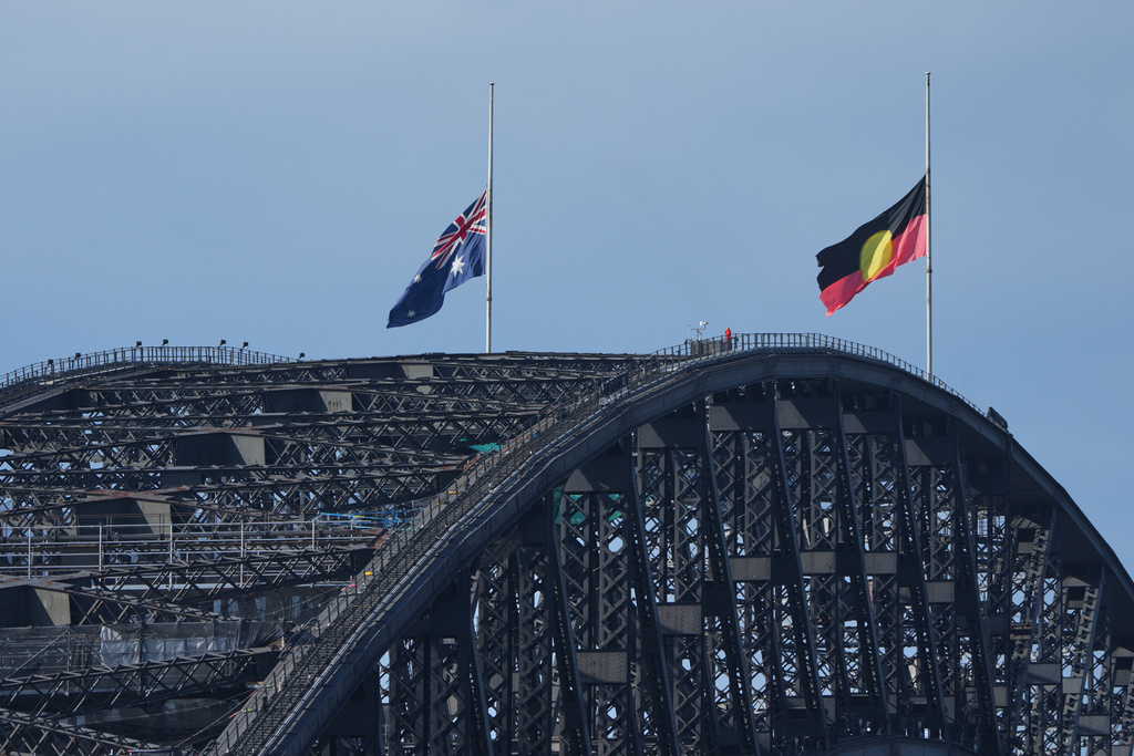 Australian and Aboriginal flags fly at half staff on the Sydney Harbour Bridge during a National Day of Reflection to honour the victims of the last Sunday's terrorist attack at Bondi Beach, Sunday, Dec. 21, 2025. (AP Photo/Mark Baker)