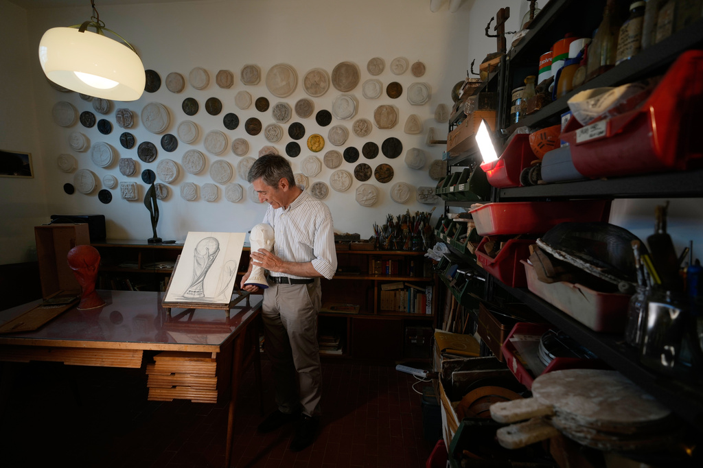 Giorgio Gazzaniga, son of the late sculptor Silvio Gazzaniga, holds the original plaster World Cup trophy sculptur at a warehouse in Pioltello, Italy, Saturday, July 11, 2026. (AP Photo/Luca Bruno)