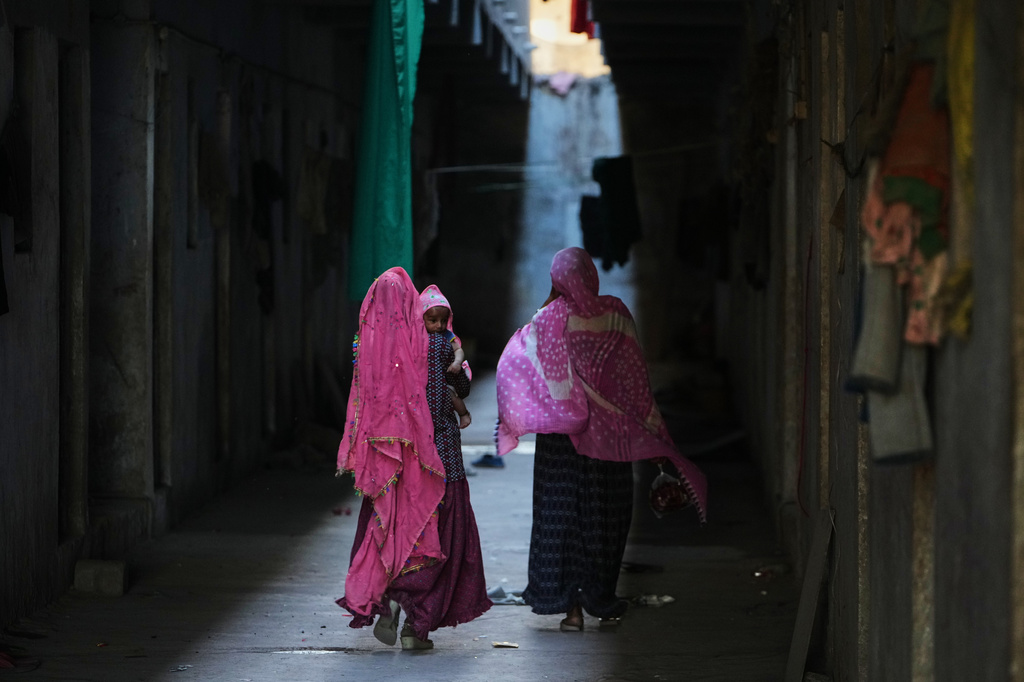 A family of migrant workers returns to their quarters in Morbi, in the Indian state of Gujarat, Wednesday, April 8, 2026. (AP Photo/Ajit Solanki)