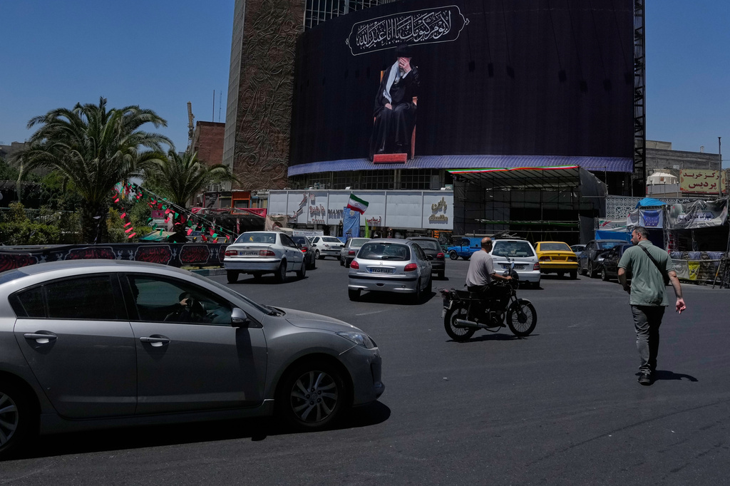 People pass under a billboard showing a portrait of the slain Iranian Supreme Leader Ayatollah Ali Khamenei, who was killed in U.S. and Israeli strikes on Feb. 28, in downtown Tehran, Iran, Monday, June 15, 2026. (AP Photo/Vahid Salemi)