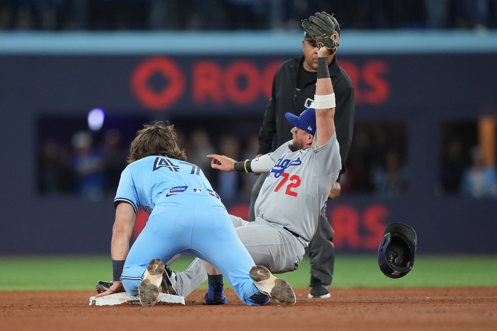 Los Angeles Dodgers second baseman Miguel Rojas (72) shows the ball to the umpire after forcing out Toronto Blue Jays' Addison Barger (47) at second to turn a double play to end the game during ninth inning Game 6 World Series playoff MLB baseball action in Toronto on Friday, Oct. 31, 2025. (Nathan Denette/The Canadian Press via AP)