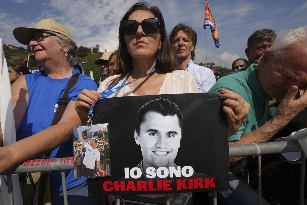 A woman holds a photo of Charlie Kirk that reads: "I am Charlie Kirk", during the League party's annual gathering in Pontida, north of Italy, Sunday, Sept. 21, 2025. (AP Photo/Antonio Calanni)
