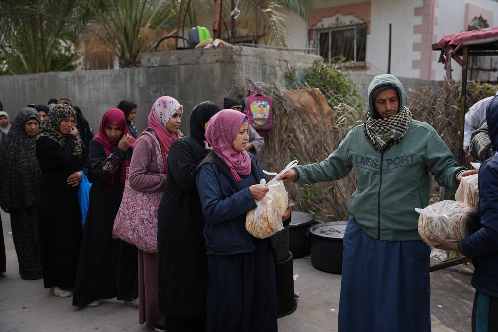 Palestinian women line up to receive donated food at a community kitchen in Deir al-Balah, central Gaza Strip, Wednesday, Jan. 21, 2026. (AP Photo/Abdel Kareem Hana)
