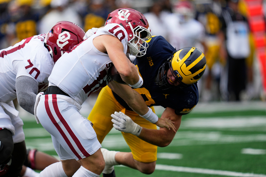 Michigan defensive end John Henry Daley (90) tackles Oklahoma quarterback John Mateer (10) in the first half of an NCAA college football game Saturday, Sept. 12, 2026, in Ann Arbor, Mich. (AP Photo/Paul Sancya)