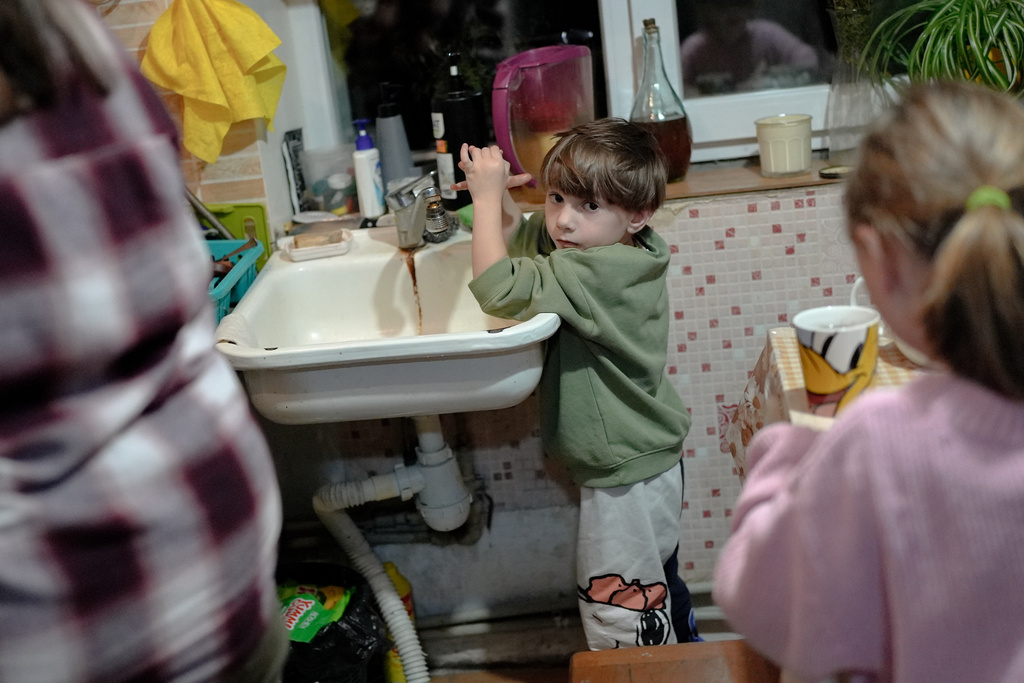 CORRECTS FAMILY NAME TO ADAMCHUK - Oleksandr Adamchuk's son, Sashko, 4, attempts to wash his hands during dinner, only to be met by a water outage, Friday, Oct. 24, 2025, at the family's home in Kyiv region, Ukraine. (AP Photo/Julia Demaree Nikhinson)