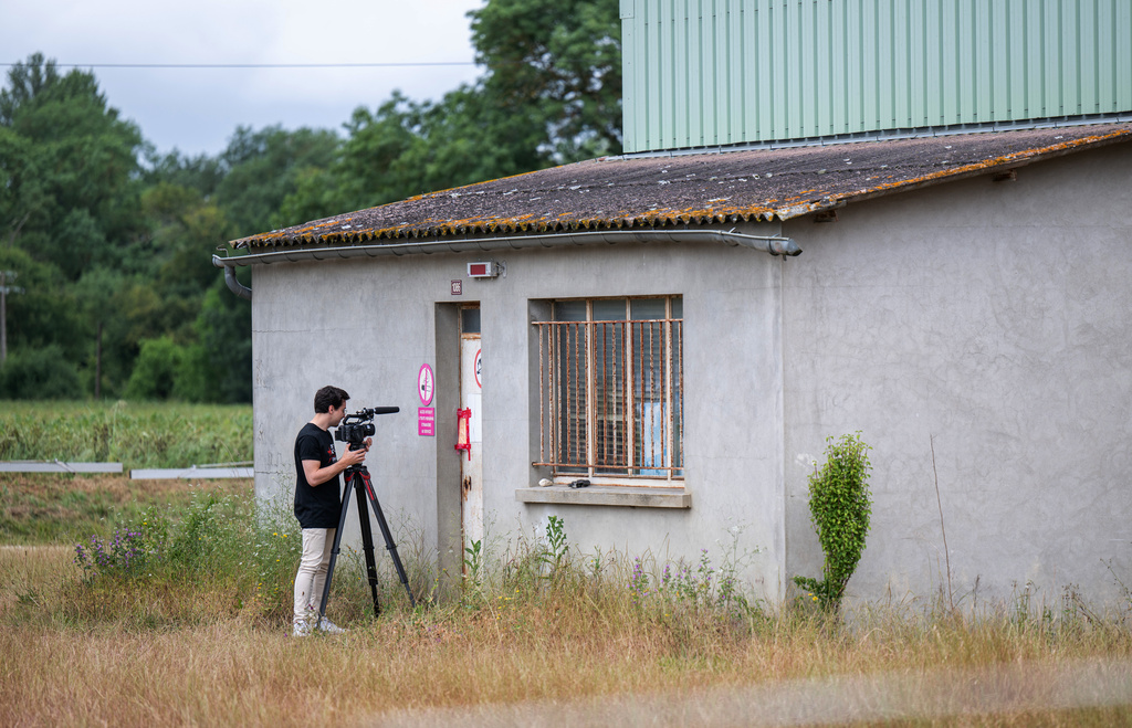 A videographer films the entrance of a farm silo where a body was found yesterday during the search to find missing 11 year-old girl Lyhanna in Puycasquier, southwestern France, Friday, June,5, 2026. (AP Photo/Frederic Lancelot)