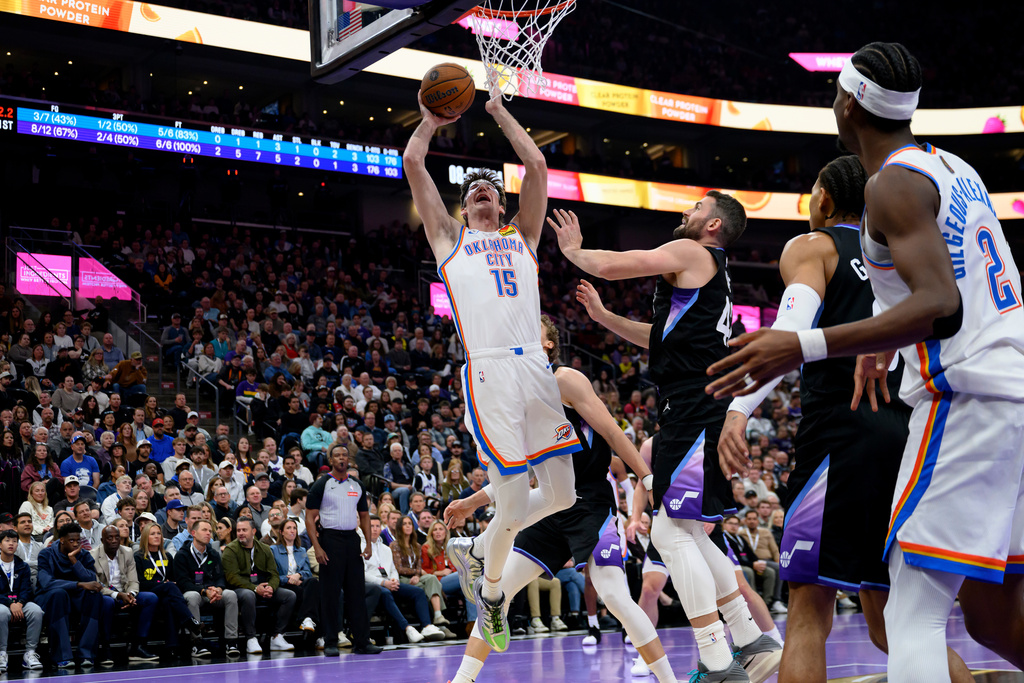 Oklahoma City Thunder center Branden Carlson (15) drives to the basket guarded by Utah Jazz forward Kevin Love, center right, during the first half of an NBA Cup basketball game, Friday, Nov. 21, 2025, in Salt Lake City. (AP Photo/Tyler Tate)
