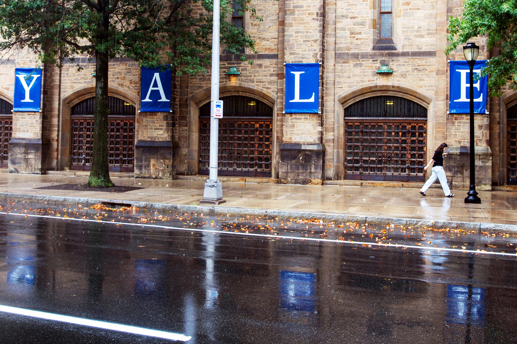 FILE - A woman walks by a Yale sign reflected in the rainwater on the Yale University campus in New Haven, Conn., Aug. 22, 2021. (AP Photo/Ted Shaffrey, File)