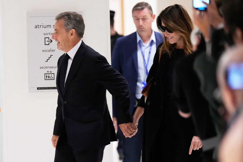 Former French President Nicolas Sarkozy and his wife Carla Bruni Sarkozy arrive to the courtroom for his verdict for alleged illegal financing of his 2007 presidential campaign by the government of then-Libyan leader Moammar Gadhafi, Thursday, Sept. 25, 2025 in Paris. (AP Photo/Michel Euler)