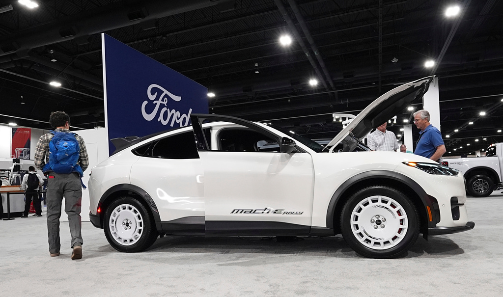 FILE - Shoppers look over a 2025 Mach-E electric utility vehicle in the Ford display at the Colorado Auto Show, April 17, 2025, in Denver. (AP Photo/David Zalubowski, File)