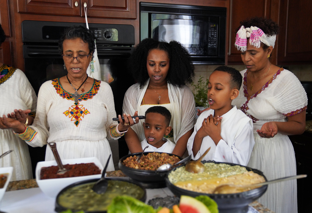 Members of the Tekola family pray together before breaking their 55-day fast on Easter Sunday, April 12, 2026, in Triangle, Va. (AP Photo/Jessie Wardarski)