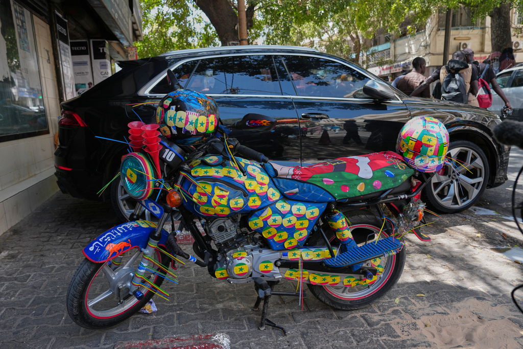 A motorcycle decorated with Senegalese colorful stickers is parked along a street in Dakar, Senegal, Wednesday, March 18, 2026. (AP Photo/Misper Apawu)