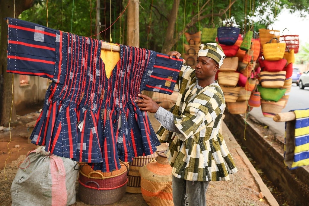 Clement Azaabire hangs traditional fugu garments under a tree on display for sale along a street in Accra, Ghana, Wednesday, Feb. 18, 2026. (AP Photo/Tsraha Yaw)