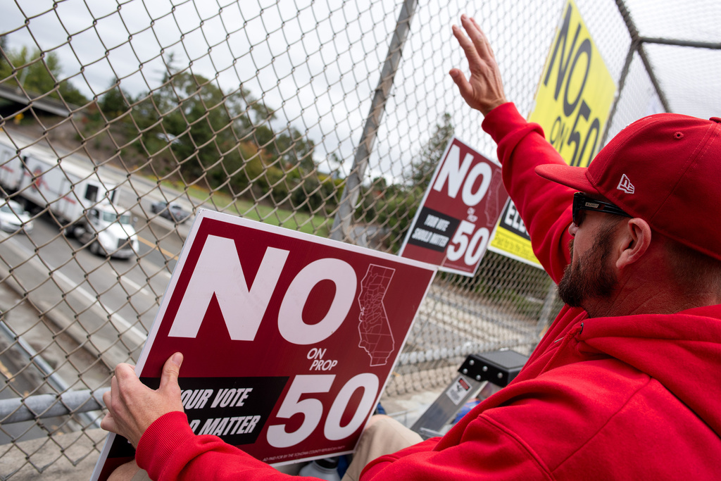 Ryan Sherron of Santa Rosa waves to a truck driver sounding an air horn in support of people voting No on Prop 50, at a pedestrian overpass above Highway 101 in Santa Rosa, Calif., on Tuesday Nov. 4, 2025. (Alvin A.H. Jornada/San Francisco Chronicle via AP)