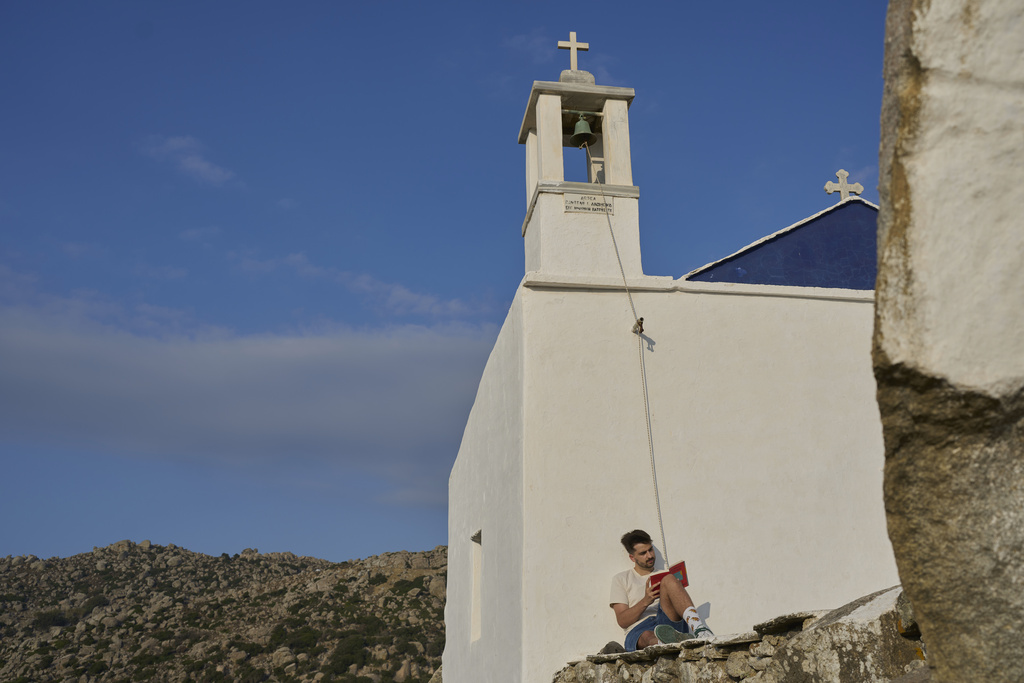 Giannis Kafantaris, 26, reads a book outside Panagia Theoskespasti, the chapel his family co-owns near the village of Falatados, on the Aegean island of Tinos, Greece, Friday, Sept. 5, 2025. (AP Photo/Petros Giannakouris)