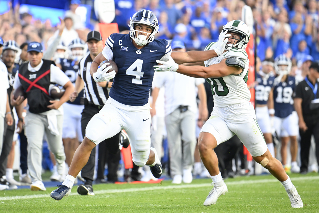 BYU running back LJ Martin (4) runs past Portland State linebacker Lonnie Burt (40) during the first half of an NCAA college football game, Saturday, Aug. 30, 2025 in Provo. (AP Photo/Alex Goodlett)