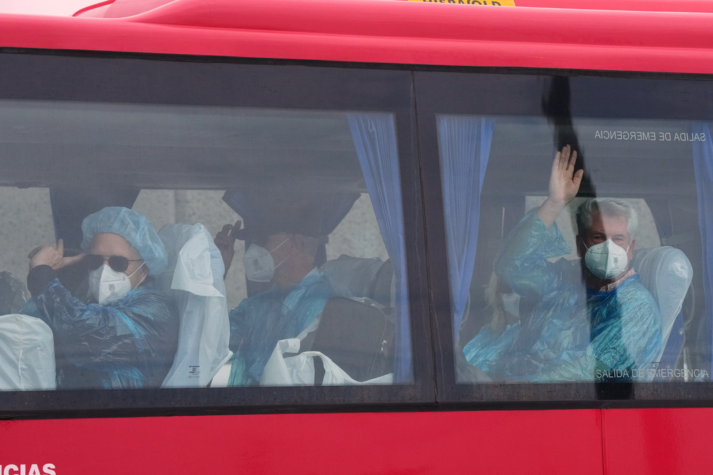 Passengers wave inside a bus after being disembarked from the hantavirus-stricken cruise ship MV Hondius at the port of Granadilla in Tenerife, Canary Islands, Spain, Sunday, May 10, 2026. (AP Photo/Manu Fernandez)