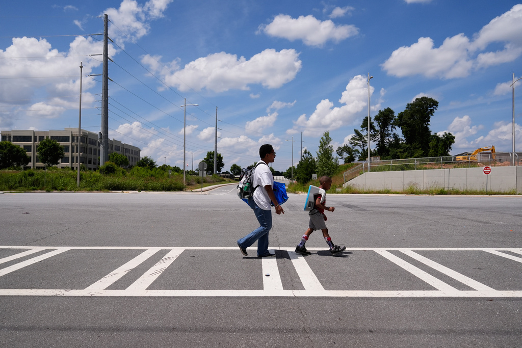 Derrick McNair-White, left, walks with Sechita McNair to catch the bus to Atlanta on June 6, 2025. (AP Photo/Brynn Anderson)