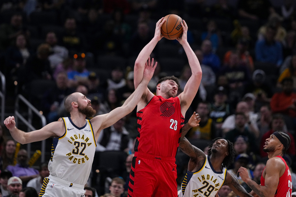 Portland Trail Blazers center Donovan Clingan (23) grabs a rebound between Indiana Pacers center Jay Huff (32) and guard Quenton Jackson (29) during the first half of an NBA basketball game in Indianapolis, Wednesday, March 18, 2026. (AP Photo/Michael Conroy)