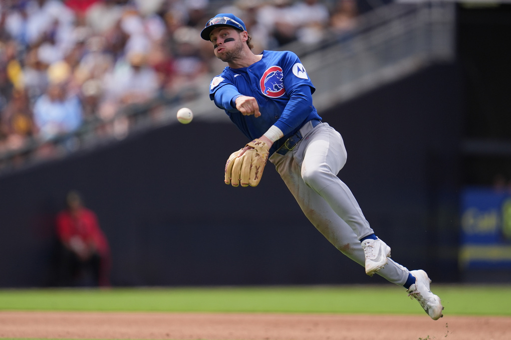 Chicago Cubs shortstop Nico Hoerner throws to first too late as San Diego Padres' Fernando Tatis Jr. arrives safely with a single during the sixth inning of a baseball game Wednesday, April 29, 2026, in San Diego. (AP Photo/Gregory Bull)