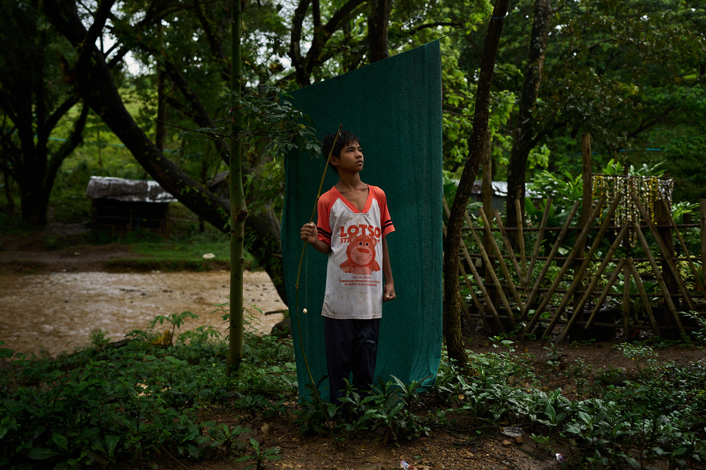 Twelve-year-old Mohama poses for a portrait with his fishing rod along the river that winds past his refugee camp in the Tak province of Thailand, Wednesday, Aug. 27, 2025. (AP Photo/Bram Janssen)