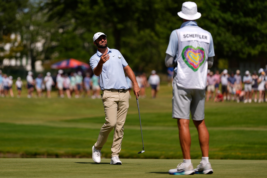 Scottie Scheffler tosses his ball to his cadie on the 11th green during the final round of the St. Jude Championship golf tournament, Sunday, Aug. 16, 2026, in Memphis, Tenn. (AP Photo/George Walker IV)