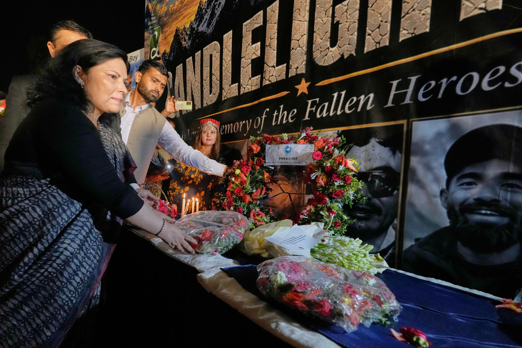 Nepalese Ambassador to Pakistan Rita Dhital, left, and others place flowers next to pictures of climbers who lost their lives on Broad Peak, during a candlelight vigil in their memory, in Islamabad, Pakistan, Tuesday, Aug. 11, 2026. (AP Photo/Anjum Naveed)