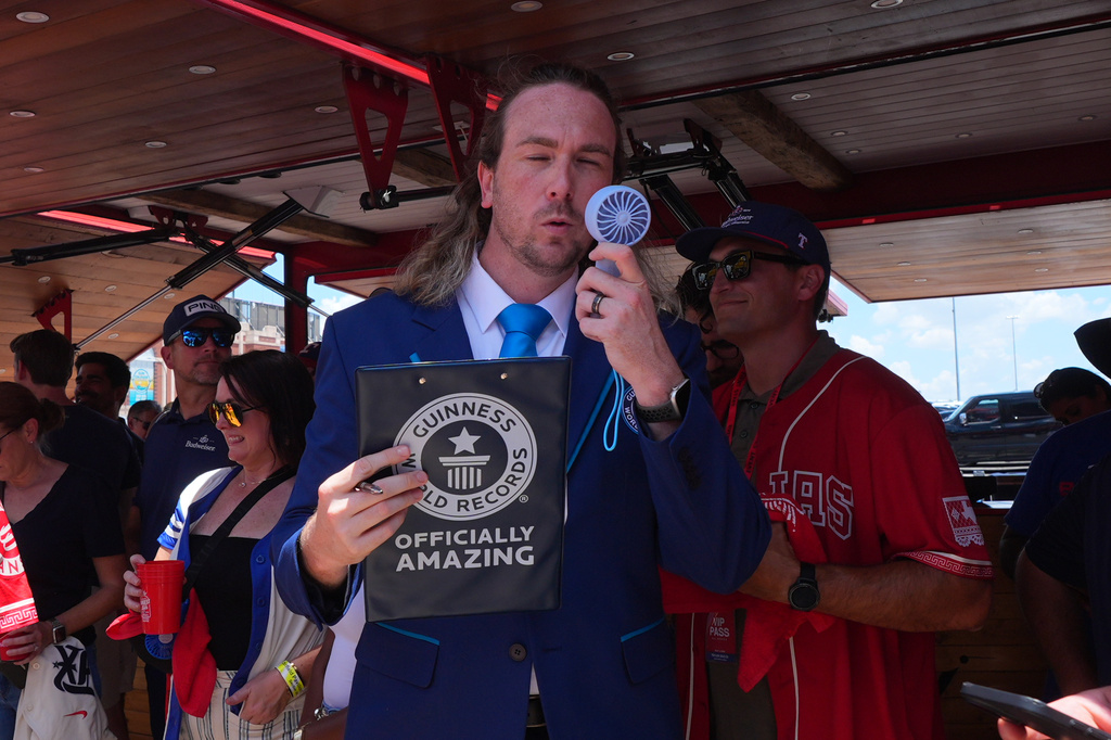 Guinness World Records adjudicator Thomas Bradford uses a fan to cool off before certifying a world record for Largest Glass of Beer ahead of a baseball game between the Detroit Tigers and Texas Rangers, Saturday, July 4, 2026, in Arlington, Texas. (AP Photo/LM Otero)