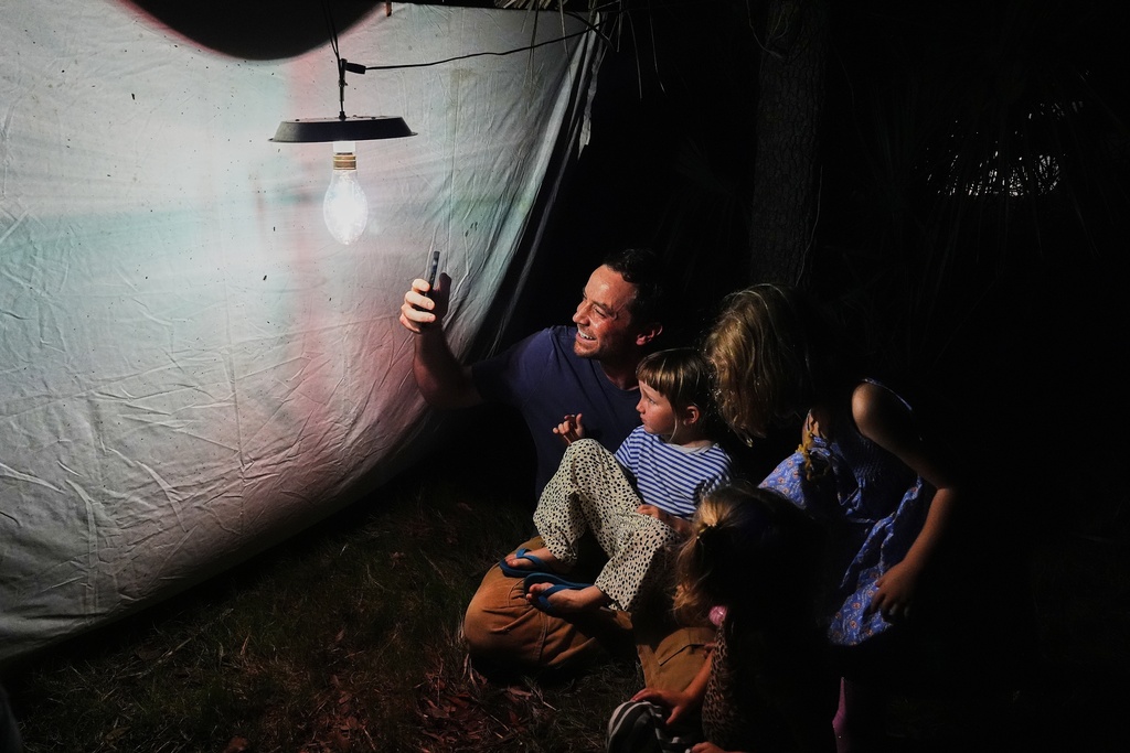 Joel Caldwell, left, sits with his daughter, Land, third from right, along with Raya Scott, second from right, and Agnes Suárez while observing pollinators Tuesday, Oct. 7, 2025, in Charleston, S.C. (AP Photo/Joshua A. Bickel)